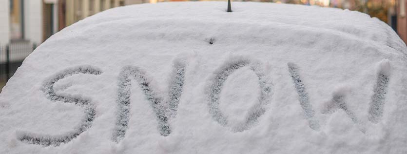 snow écrit sur la vitre arrière d'une voiture enneigée